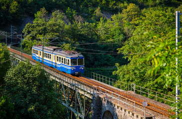 Historic electric train on famous steel bridge in Intragna in Centovalli valley. Famous narrow...