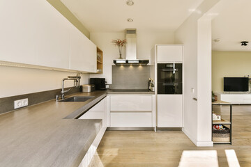a kitchen with white cabinets and black counter tops on the island in front of the sink is open to the living room