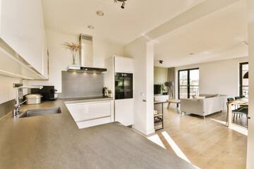 a kitchen and living room in a house or apartment with white walls, hardwood flooring and stainless steel appliances