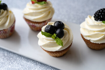 Cupcakes with different fruits on a white plate close-up.