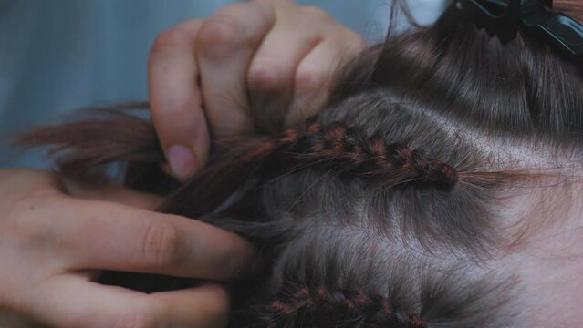 Process of weaving making boxer braids cornrows by a hair braider.