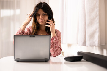 Woman talking on the phone thinking with the laptop in front of her