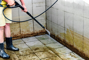 Swimming pool cleaning. A service man is cleaning the pool ground with a high-pressure washer.