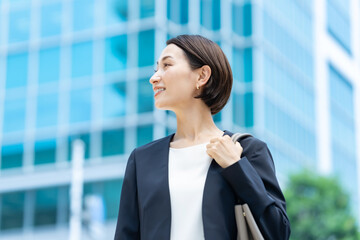 オフィスビルの前に立つビジネス女性