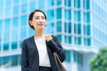 オフィスビルの前に立つ考えるビジネス女性