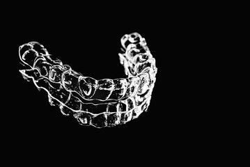 Invisible aligners retainers of teeth lie on the mirror on a black and white photograph