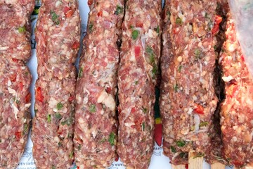 Raw Adana kebab on a plate, ready for grill