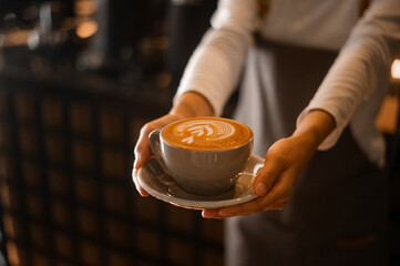 Fototapeta na wymiar Latte art in barista hand ready to drink in modern coffee shop
