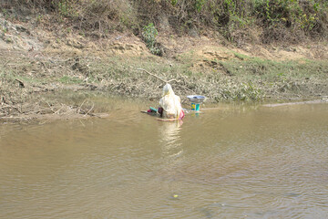 a woman is washing cloth in stream in bangladesh