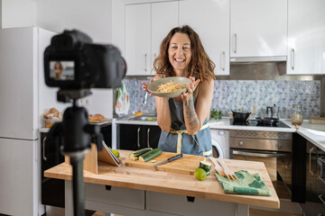 adult woman recording herself with the camera while cooking for her healthy food blog