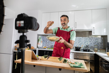 adult man recording herself with the camera while cooking for her healthy food blog
