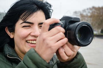 portrait of young latin woman smiling taking a picture with her DSLR digital camera