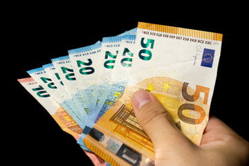 Close-up of one hand with exchange a 50, 10 and 20 euro notes to buy and sell. 10, 20, 50 EURO notes. Changes in wages and taxes. Rising inflation. EUR Cash money banknotes background.