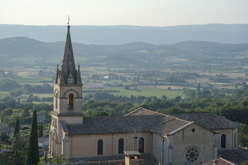 View on Saint-Gervais church in of old medieval town Bonnieux, Provence, France. Beautiful view of the valley with lavender fields and vineyards.
