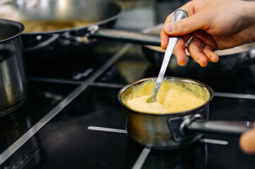 Chef hands cooking cheese sauce in the restaurant kitchen