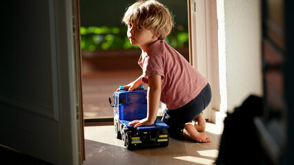 Little boy playing with truck at home by the doorstep toddler plays with toy vehicle