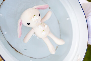A white toy rabbit in a bowl of water