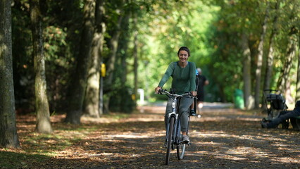 Mother and child riding bicycle kid in bike back seat wearing helmet rides together with parent