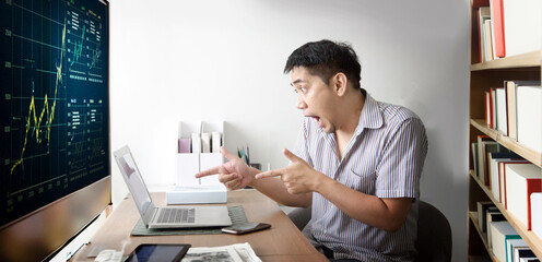 Fototapeta na wymiar Asian man chocking action and point to laptop screenwhen win stock market on his room