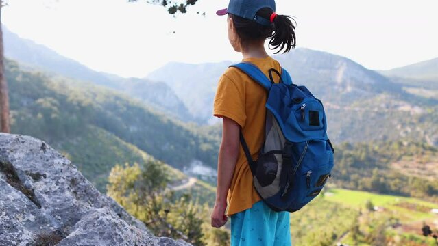 Traveling child. a tourist with a backpack stands on a mountain path looks at the mountains. hiking and active healthy lifestyle. adventure holidays with children.