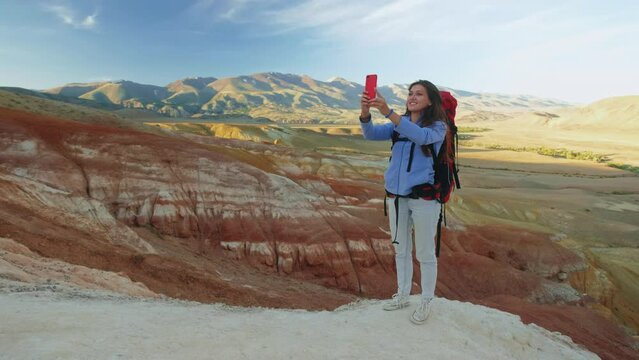 Woman hiker on top of the mountain takes a photo. Female traveler takes a photo on a modern smartphone, makes beautiful pictures of beautiful mountain landscapes. mountain climbing and adventure.