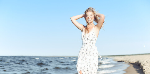 Happy blonde beautiful woman having fun on ocean beach while dancing in waves