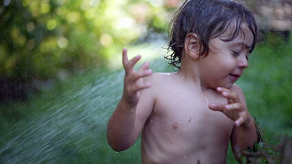 Water hosing child during summer day outside little boy enjoying vacations running and laughing