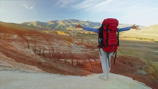 Hiker woman standing with hands up achieving the top. Girl welcomes a sun. Successful woman hiker open arms on sunrise mountain top. Freedom, sport, success and mental health concept