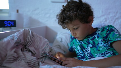 Youyng boy using cellphone in bedroom staring at screen