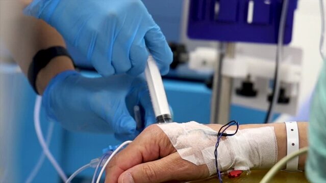 4K close up footage of nurse injecting antibiotic to patient's IV drip. Patient bandaged hand and nurse hands in glow stock video.