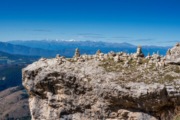 Group of cairns piles of stone on rock against blue sky