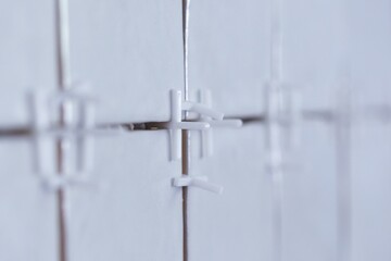 A close up portrait of plastic white joint spacers placed in the juncture of a recently tiled wall...