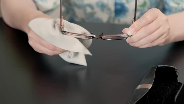 Women cleaning fashion glasses lenses with a light microfiber cloth. healthcare, vision and medicine concept