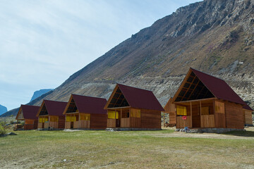 Wooden houses against mountains and clear sky at dawn. Tourist base in Altai, Stone Mushrooms