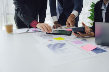 Business documents on office table with smart phone and calculator digital tablet and graph business with social network diagram and two colleagues discussing data working in office
