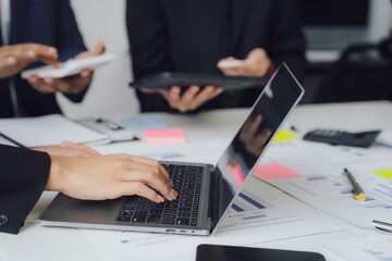 Business documents on office table with smart phone and calculator digital tablet and graph business with social network diagram and two colleagues discussing data working in office