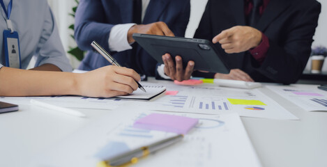 Business documents on office table with smart phone and calculator digital tablet and graph business with social network diagram and two colleagues discussing data working in office