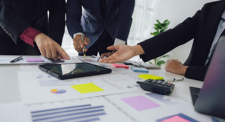 Businessman and team analyzing financial statement Finance task. with smart phone and laptop and tablet. Wealth management concept at office