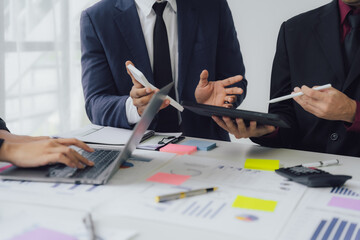 Businessman and team analyzing financial statement Finance task. with smart phone and laptop and tablet. Wealth management concept at office