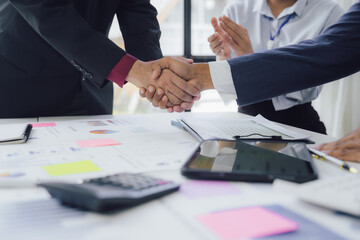 Obraz premium Business documents on office table with smart phone and calculator digital tablet and graph business with social network diagram and two colleagues discussing data working in office