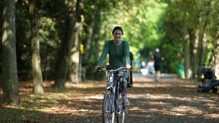 Mother riding bicycle with child in bike back seat outside in nature
