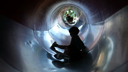 One fun kid sliding down inside tunner slider at playground