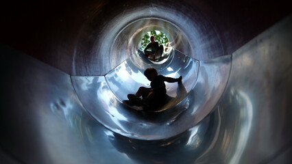 One fun kid sliding down inside tunner slider at playground