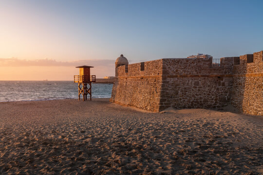 Orejon Bastion and Lifeguard Tower at La Caleta Beach at sunset - Cadiz, Andalusia, Spain