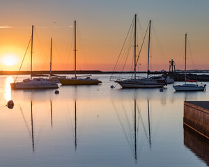 Fototapeta na wymiar Sunset in the port of Juan Lacaze, with several sailboats anchored in the foreground