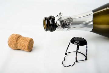 Cork and empty champagne bottle on white