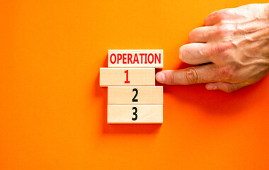 Time to operation 1 symbol. Concept word Operation 1 2 3 on wooden block. Businessman hand. Beautiful orange table orange background. Business planning and time to operation 1 concept. Copy space.