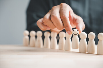Hand choosing a wooden figure from a group of crowd for business hiring and recruitment. The...