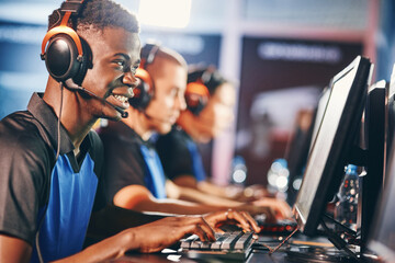 Side view of a young excited african guy, male cybersport gamer wearing headphones playing online video games while participating with team in eSport tournament