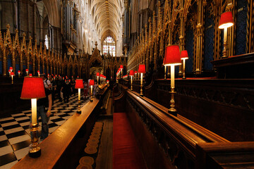 Lamps and pews line the interior of an abbey in London